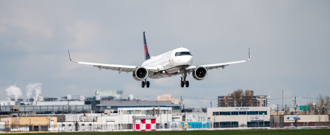 Avião da Air Canada em aproximação para aterragem junto a uma zona aeroportuária.
