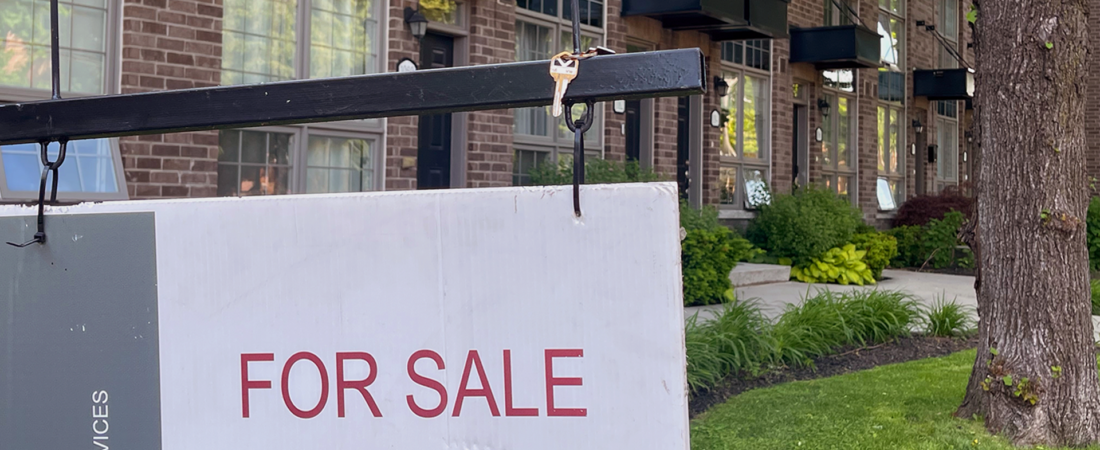 Cartaz “For Sale” em frente a um edifício residencial na Grande Área de Toronto.