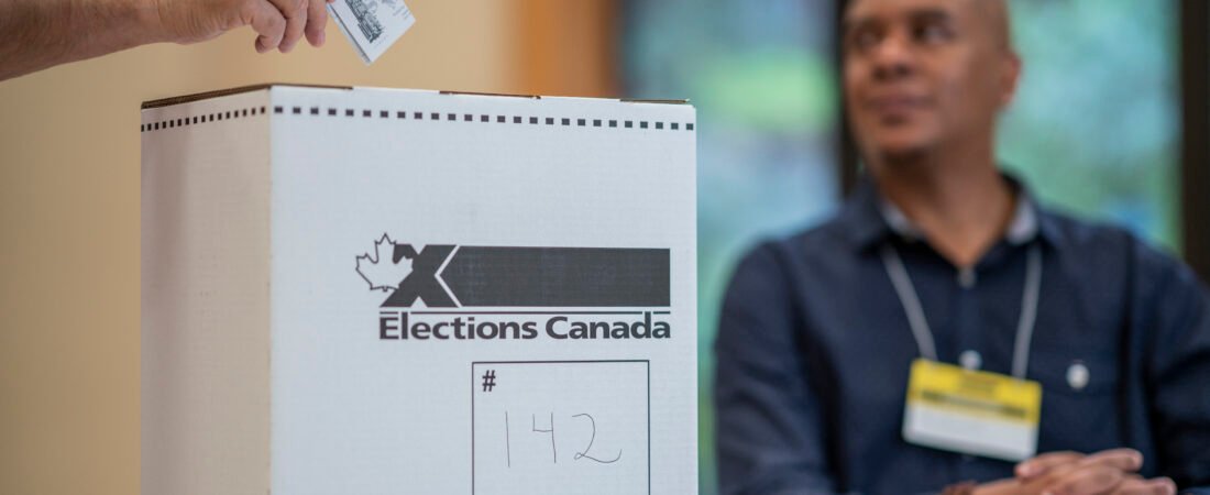 Eleitor deposita um boletim numa urna da Elections Canada num local de votação.